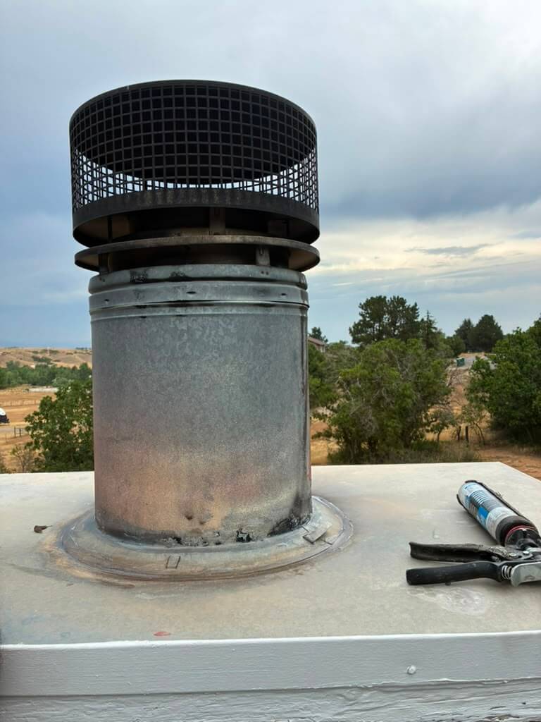 The finished cap, sealed and drafting New black stainless spark-arrestor chimney cap installed and sealed on a metal flue in Arvada, Colorado